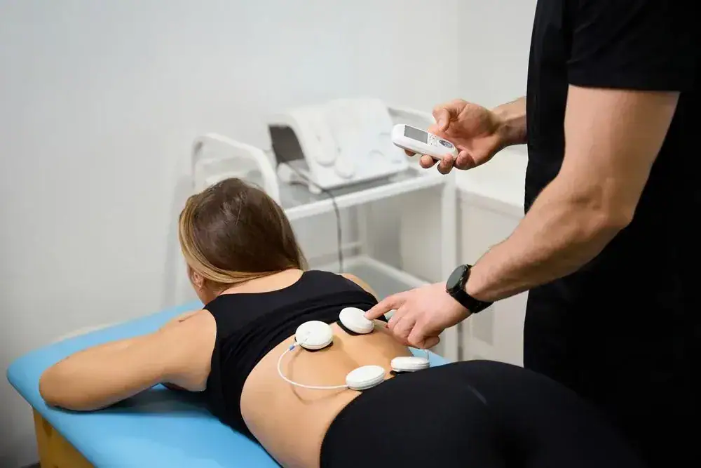 Person undergoing physiotherapy electrotherapy treatment on the back.