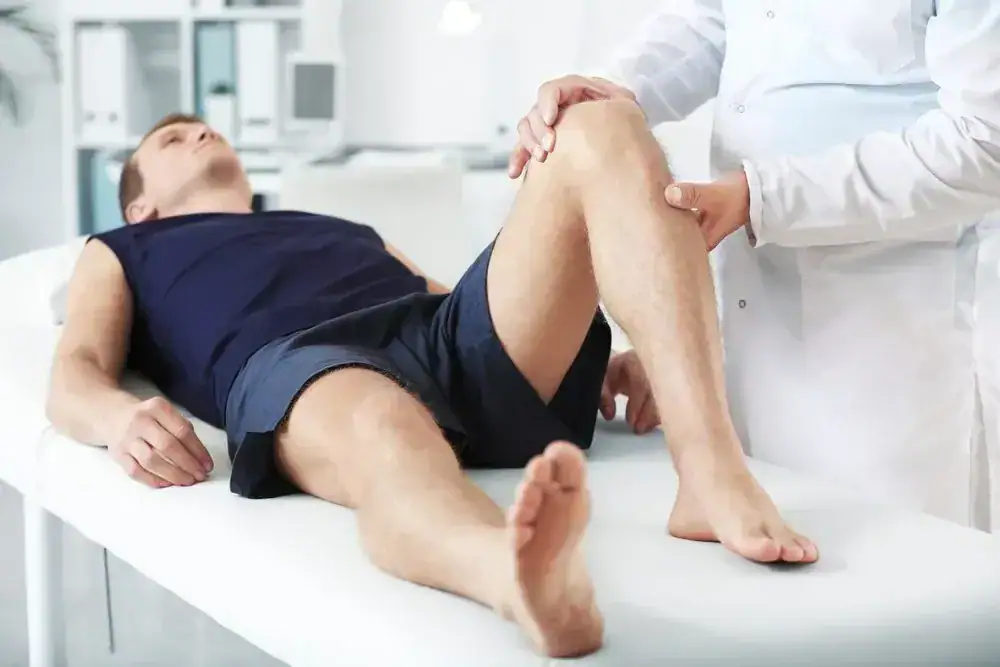 Therapist examining patient's knee during physical therapy session.
