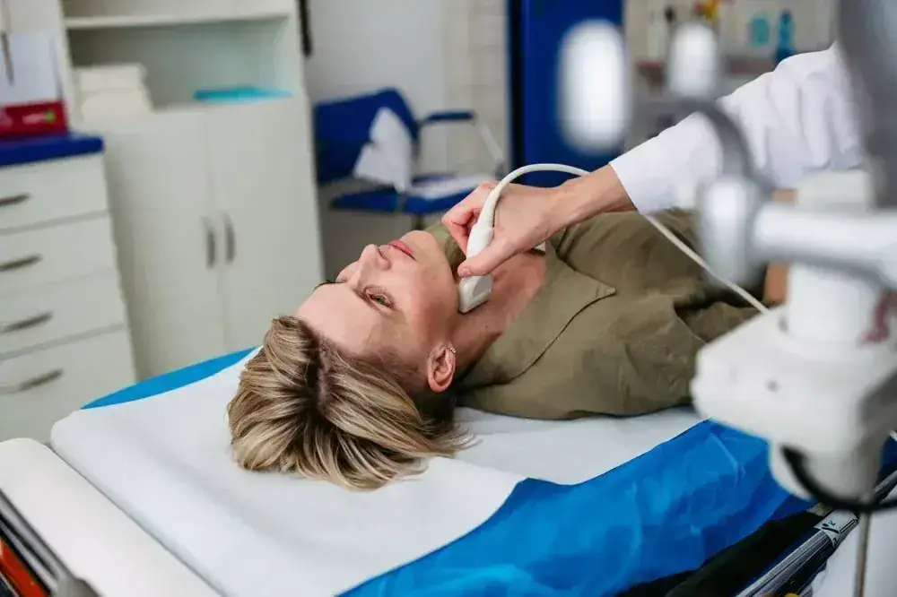 Patient laying on examination table receiving a neck ultrasound procedure.