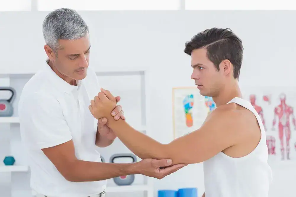 Physiotherapist assesses patient's arm movement in clinic.